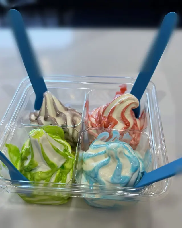 Four soft serve swirls in a sampler tray with blue spoons