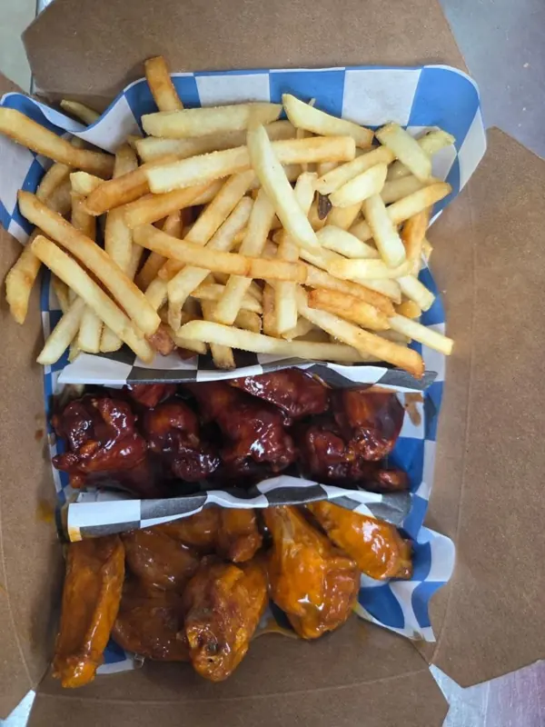 A box of fries and two kinds of wings on check paper
